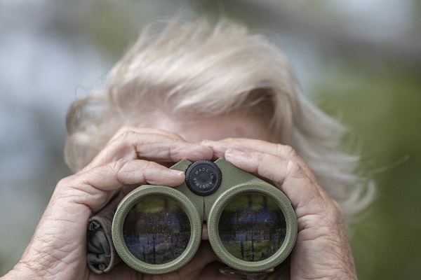 Woman holding binoculars to her eyes for birding