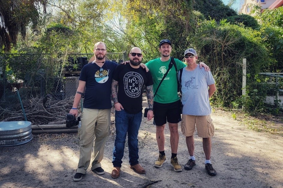 four men stand shoulder to shoulder smiling