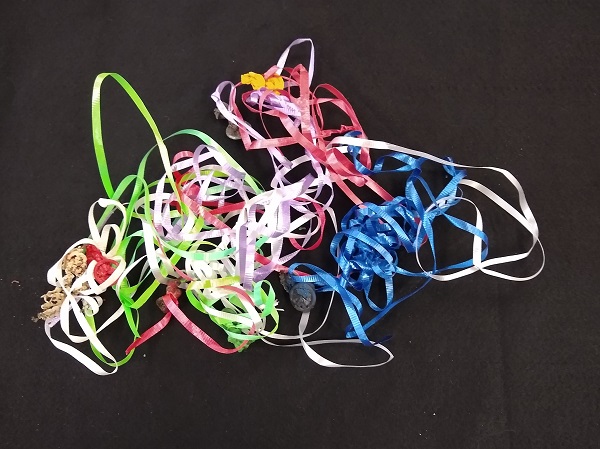 Various colors of tangled balloon strings on a black background