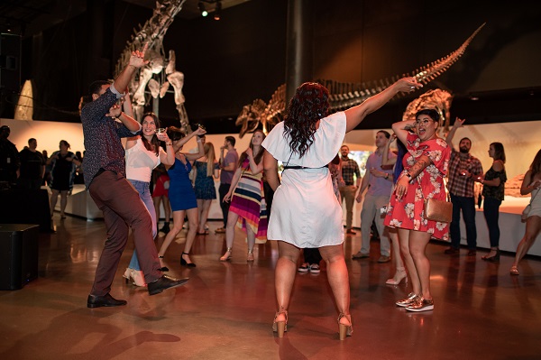 Group of people dancing in front of dinosaur fossils