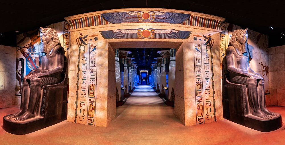 Archway of hieroglyphics and egyptian statues leading to hallway of pillars - Hall of Ancient Egypt, 2022 IES Illumination Award